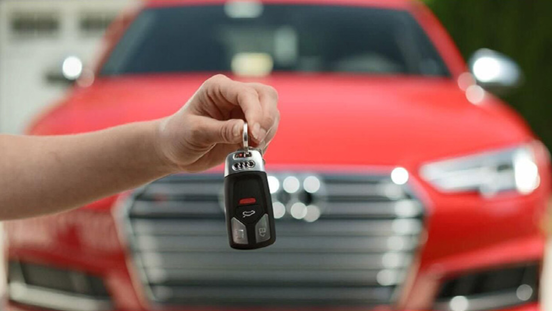 A person holding their keys out in front of their Audi. 